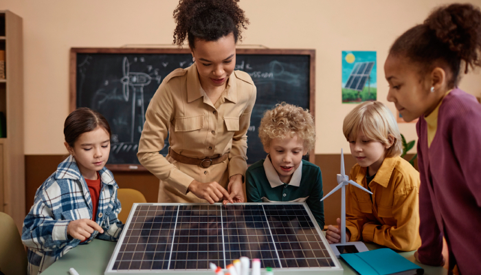 Maestra enseñando a alumnos sobre paneles solares en escuelas.